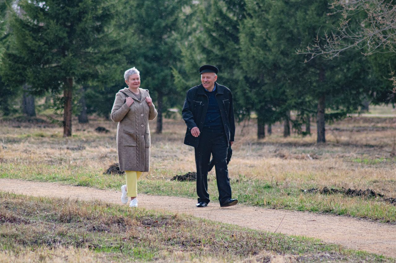 Happy senior couple strolling along a park path on a pleasant spring day.