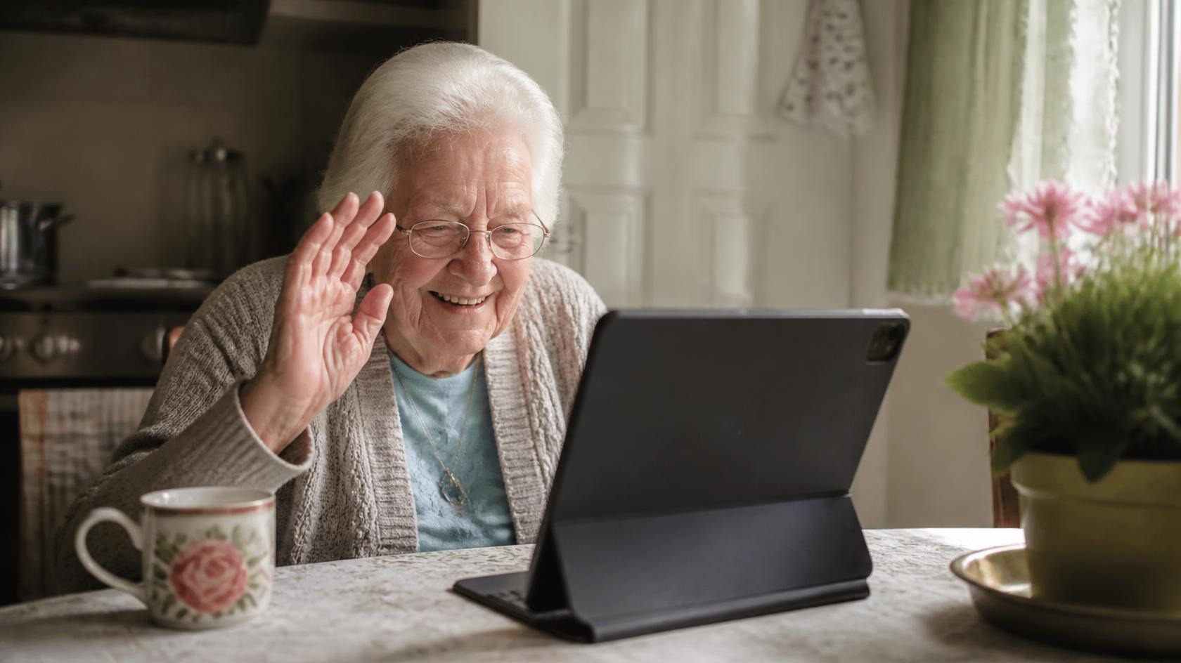 An elderly woman smiling during a video call with family on a tablet